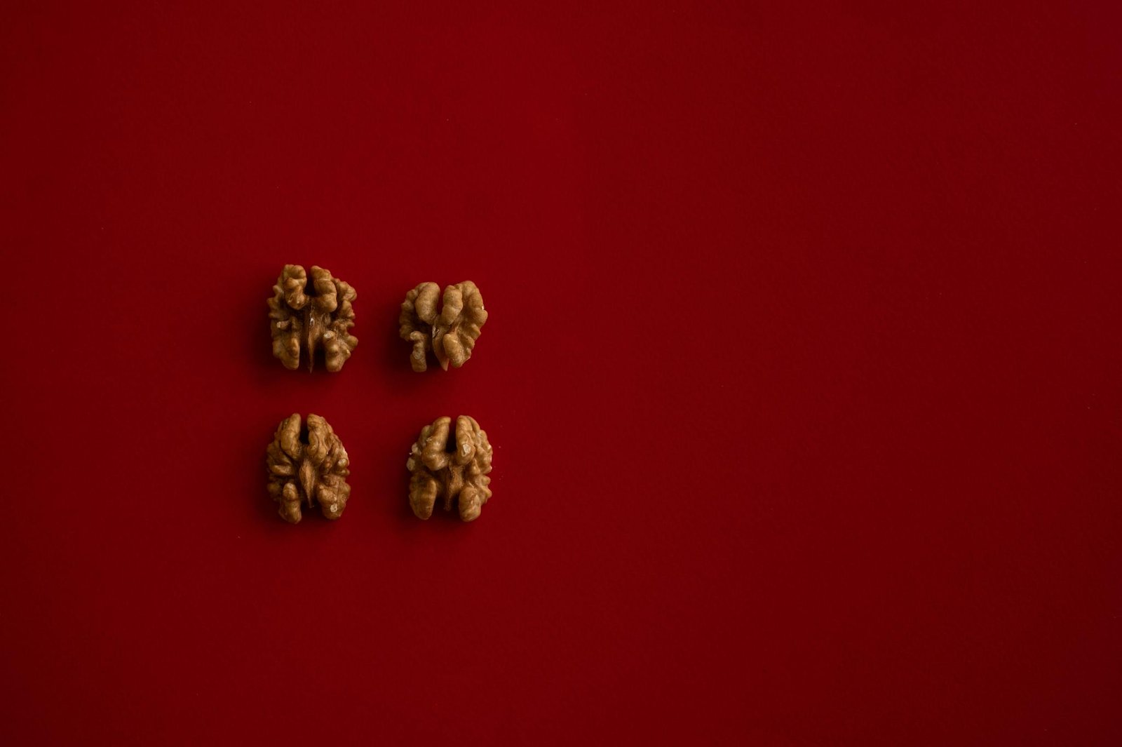 Top view of halves of walnut kernel regularly placed on dark red background